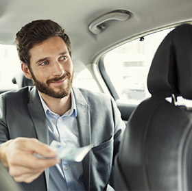 Mann in Anzug bezahlt in bar im Taxi